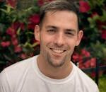 Portrait of a smiling man in front of vibrant flowers in Chicago.